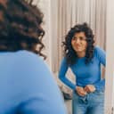 A young woman having trouble putting on tight pair of jeans