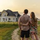 Couple holding each other and looking at a house