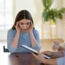 young woman stressed during a meeting, touching her temples in a modern office setting