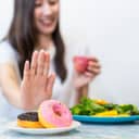 a young woman choosing a healthy salad and fruit juice over junk food