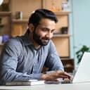 A man with a beard working on his laptop