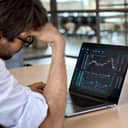 stressed businessman analyzing a downtrend in crypto trading charts in a modern office