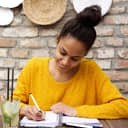 A young smiling woman writing into her journal