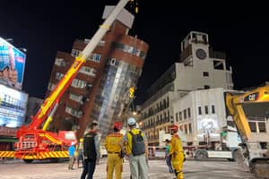 Rescue workers stand near the site of a leaning building in the aftermath of an earthquake in Hualien, eastern Taiwan on Wednesday, April 3, 2024.
