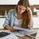Worried young woman working on finances with a laptop and calculator in front of her