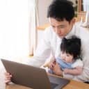 Father with a baby in his lap looking at a laptop display