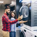 happy young couple checking out a black washing machine at an appliance store