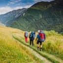 Three hikers walking down a trail in the mountains