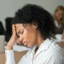 Woman with a painful expression on her face resting her head against her hand