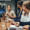 A young businesswoman guides a conversation among her team members in their contemporary workspace.