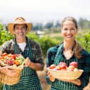 Man and woman on a farm holding fresh fruit and vegetables in baskets