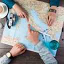 Two people pointing at a travel map on the table