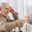 Senior man touching his head while looking at a wall calendar