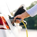 A closeup of a man plugging a charger into an EV