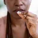 A woman preparing to take a tablet close to her mouth
