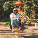 Playful man (dad) riding wooden rocking horse in a park - adult guy (hipster with beard) having fun on a playground