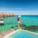 A young woman wearing a large hat at a luxurious resort in Tahiti