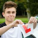 A young man ripping an L sign to show him passing a driving test