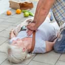 Close-up of a man administering CPR, to an elderly woman who has collapsed on the street.