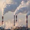 close-up of four factory smokestacks emitting smoke in the atmosphere