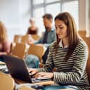 adult woman smiling and using a laptop during a university lecture
