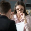 Girl with a worried expression on her face being interviewed as the interviewer reads her resume