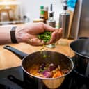 chef in the kitchen preparing Massaman curry with sweet potato and a variety of spices