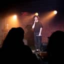 Young male comedian performing a stand-up monologue on stage at a small venue