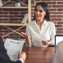 female candidate smiling during a job interview and talking about her resume, formally dressed