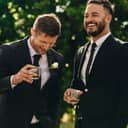 The groom and the best man drinking and smiling during a wedding party
