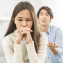 close-up of a sad woman and her husband having an argument in their living room
