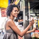 A young woman buying a hot dog from a street kiosk in New York.