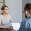 female job applicant looks surprised and stressed during an interview, panicking over an unexpected question 