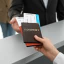 Two passports with airline tickets inside being handed over between two people