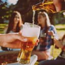 Pouring beer to a glass outside with friends