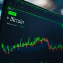 monitor displaying cryptocurrency market analytics with candlestick graphs and financial reports