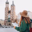 A young redhead woman, a tourist, looking at a paper map in the historic Market Square of Krakow.