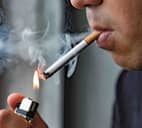 A man lighting up a cigarette in his mouth with a lighter