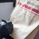 A person with leather gloves writing on an evidence envelope