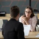 One person holding a resume interviewing another one in a modern office
