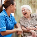 an elderly woman and a nurse laughing during a conversation