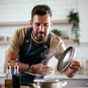 Happy man in kitchen. Young man preparing delicious food.
