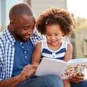 Father and daughter looking at a children's book smiling