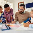 A dedicated young school teacher assisting elementary students with their writing.
