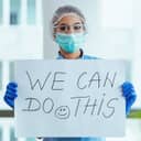 Health-care worker holding a sign saying "We Can Do This"