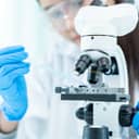 A female scientist examines biochemical samples using a microscope in a high-tech lab.