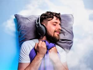 A man sleeping with headphones on covered with a blanket, a concept of dreaming