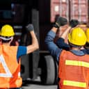 Construction workers wearing protective gear holding their hands up in the air in protest