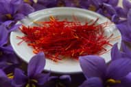 Dried saffron on a plate with saffron bloom surrounding it