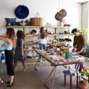 Shoppers and employees in a lively clothing store, each of them busy doing something.